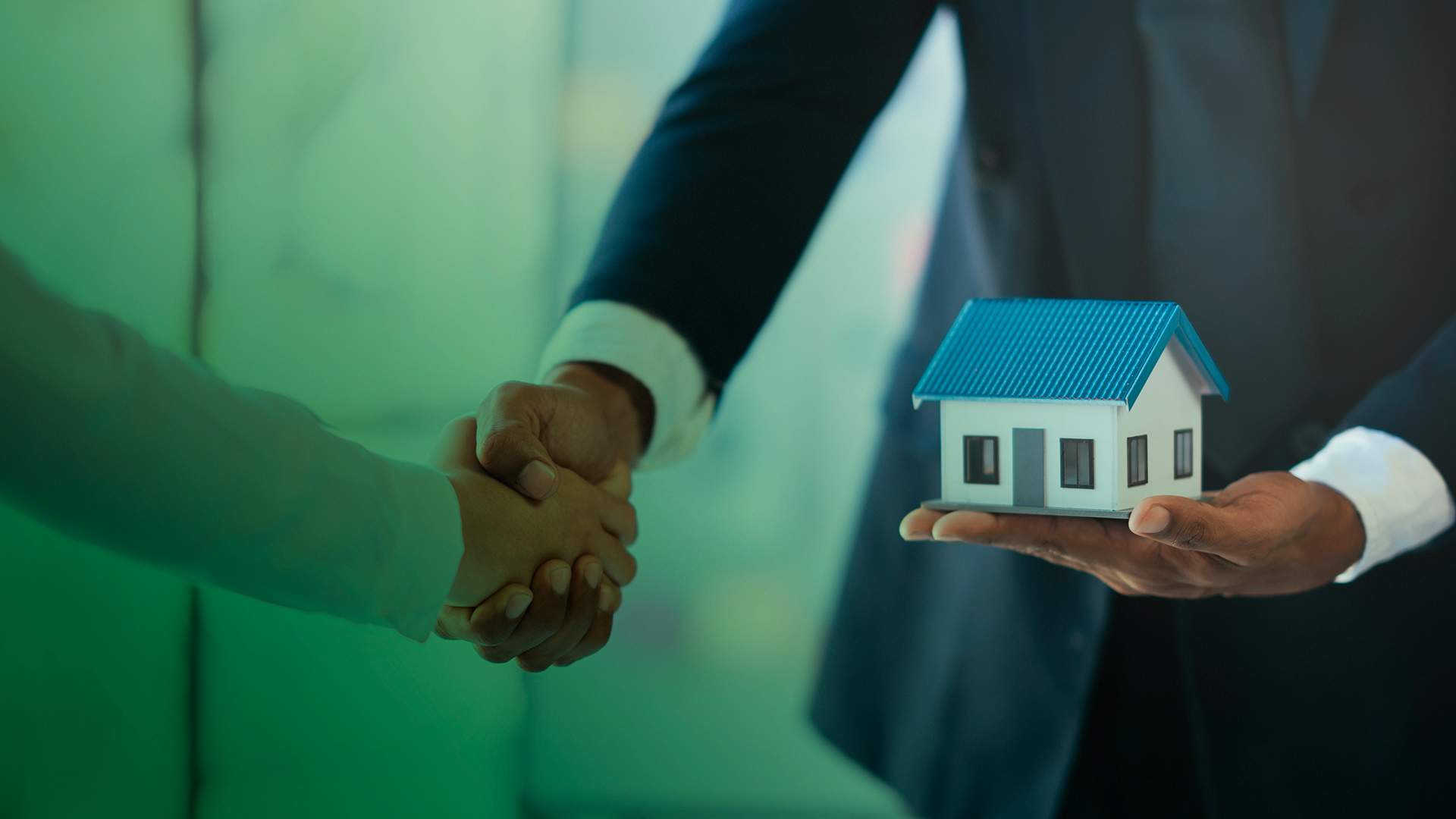 Handshake closing a property deal beside a model house